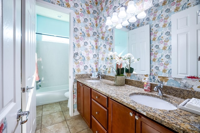 bathroom featuring tile patterned flooring, toilet, a sink, double vanity, and wallpapered walls