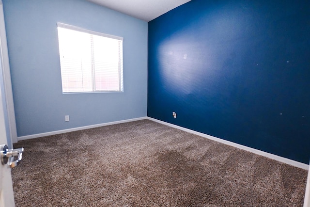 spare room featuring baseboards and carpet flooring