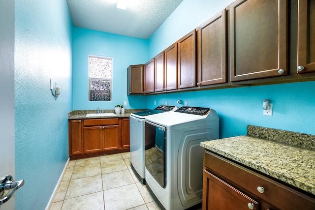 laundry room with cabinet space, light tile patterned floors, a textured ceiling, washing machine and dryer, and a sink