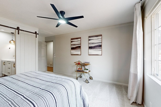 carpeted bedroom featuring ceiling fan, ensuite bath, ornamental molding, and a barn door