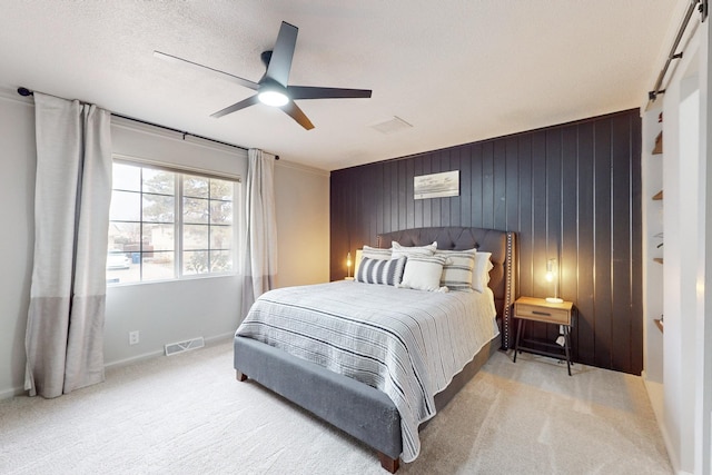 carpeted bedroom with ceiling fan, wooden walls, and a textured ceiling