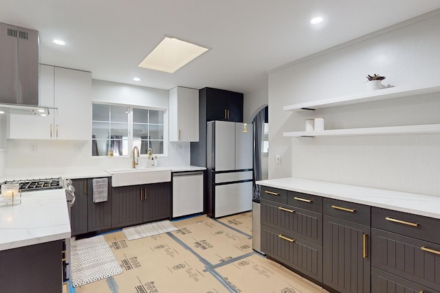 kitchen featuring white cabinetry, dishwasher, wall chimney range hood, white refrigerator, and sink