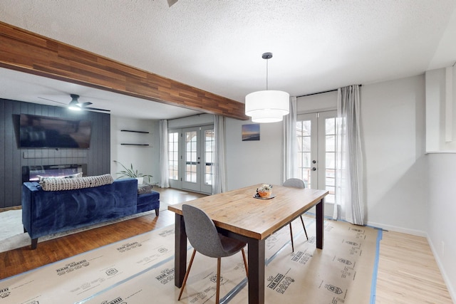 dining room featuring ceiling fan, french doors, beamed ceiling, and a textured ceiling