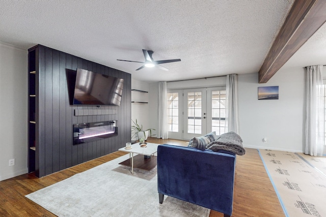 living room with ceiling fan, hardwood / wood-style floors, wooden walls, a textured ceiling, and french doors