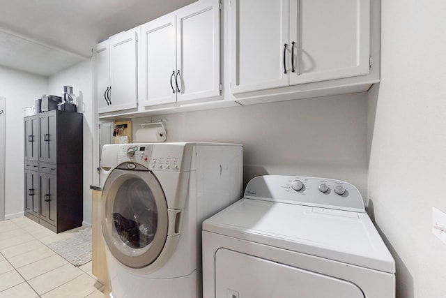 laundry area featuring cabinets, light tile patterned floors, and washer and clothes dryer