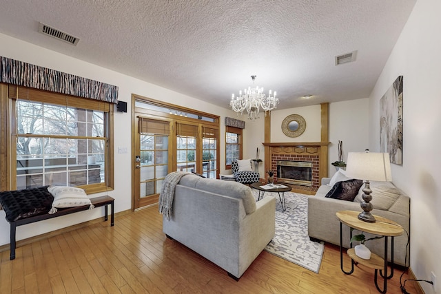 living room with wood-type flooring, a fireplace, a chandelier, and a textured ceiling