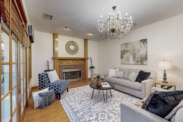 living room with wood-type flooring, a fireplace, a chandelier, and a textured ceiling