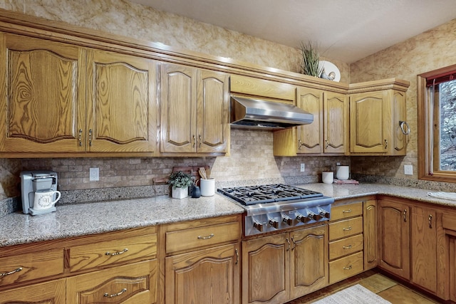 kitchen featuring stainless steel gas cooktop, light tile patterned floors, tasteful backsplash, light stone countertops, and extractor fan