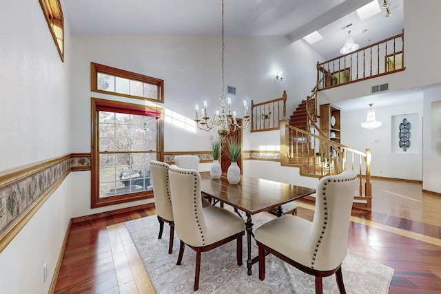 dining area with beam ceiling, an inviting chandelier, high vaulted ceiling, and wood-type flooring