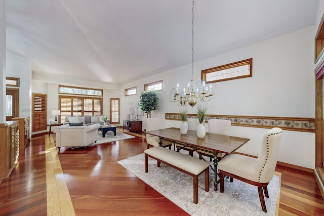 dining area featuring a towering ceiling, a chandelier, and hardwood / wood-style flooring