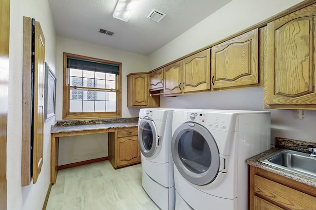 laundry room with washer and dryer, sink, light wood-type flooring, and cabinets