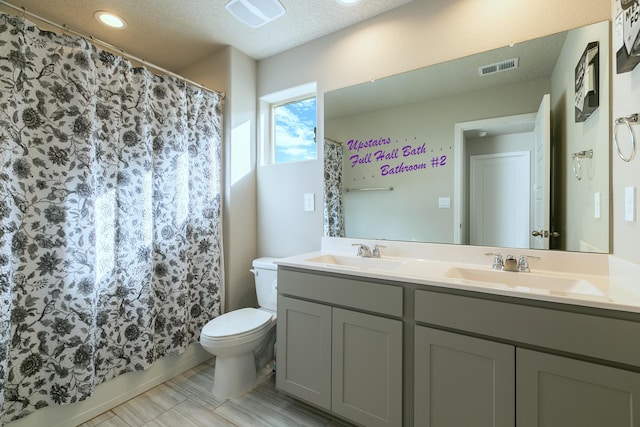 bathroom featuring a textured ceiling, toilet, and vanity