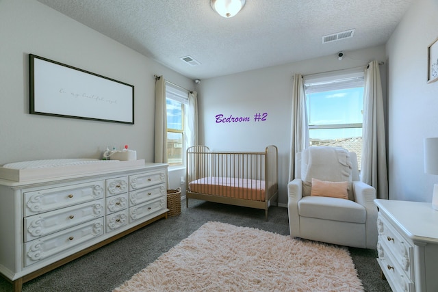 carpeted bedroom featuring a textured ceiling and a nursery area
