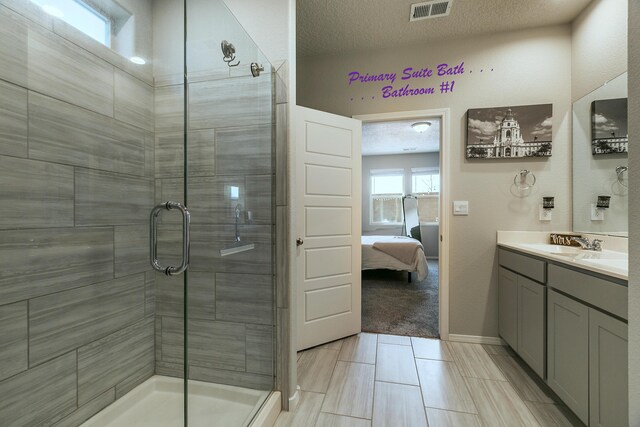 bathroom featuring a textured ceiling, a shower with door, and vanity