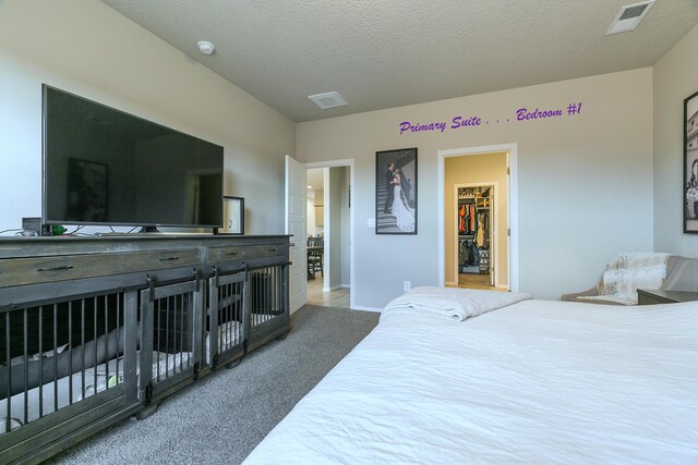 carpeted bedroom featuring a walk in closet and a textured ceiling