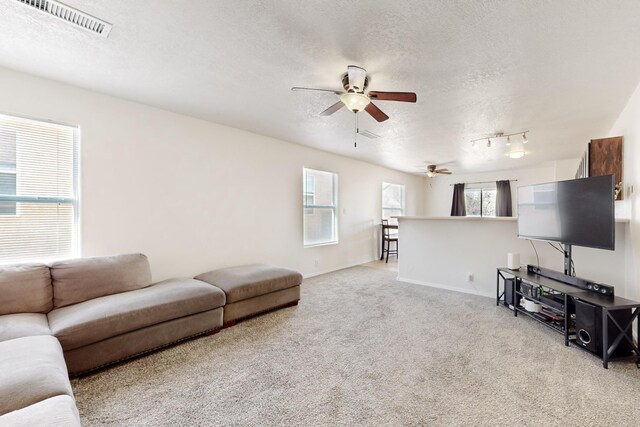 carpeted living room featuring ceiling fan, a textured ceiling, and track lighting