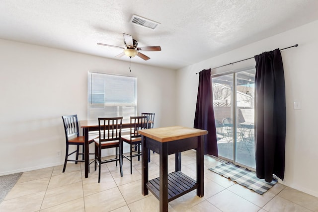 dining area with ceiling fan, a textured ceiling, and light tile patterned flooring