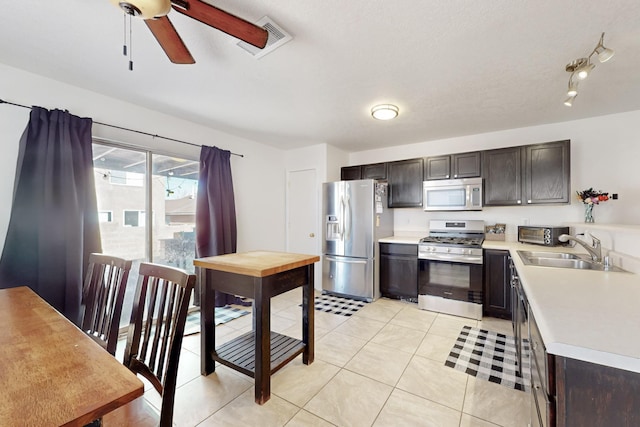 kitchen featuring sink, light tile patterned flooring, dark brown cabinets, and stainless steel appliances