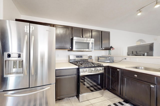 kitchen featuring sink, stainless steel appliances, dark brown cabinetry, and light tile patterned floors