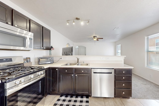 kitchen with light carpet, sink, dark brown cabinetry, kitchen peninsula, and stainless steel appliances