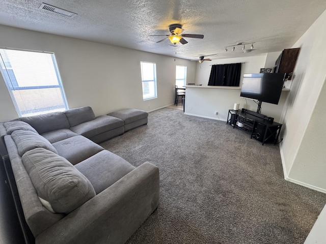 living room with a textured ceiling, rail lighting, carpet floors, and ceiling fan