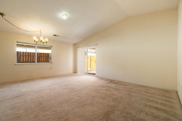 carpeted empty room with lofted ceiling and a chandelier