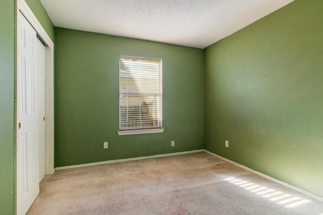 unfurnished bedroom with a closet, a textured ceiling, and light colored carpet