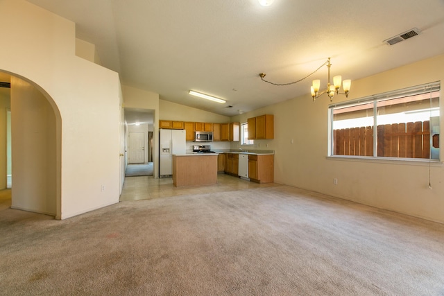 kitchen with stainless steel appliances, a center island, an inviting chandelier, lofted ceiling, and pendant lighting