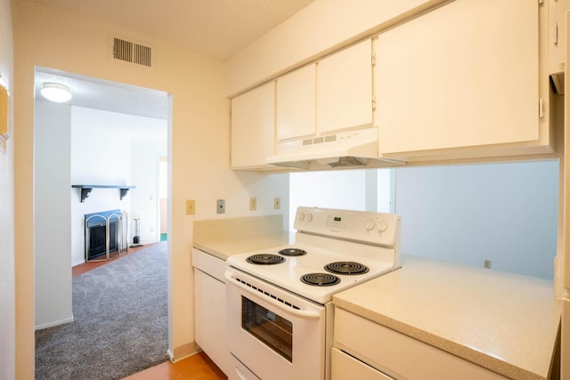 kitchen featuring white electric stove, white cabinetry, and light colored carpet