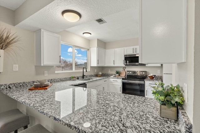 kitchen featuring light stone countertops, a textured ceiling, stainless steel appliances, white cabinets, and sink