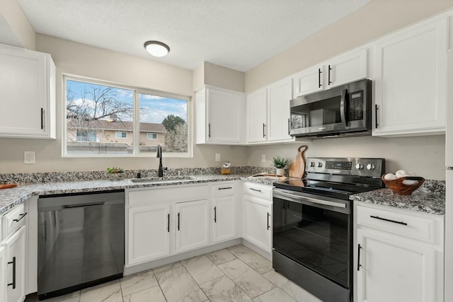 kitchen with stainless steel appliances, white cabinetry, sink, and light stone counters