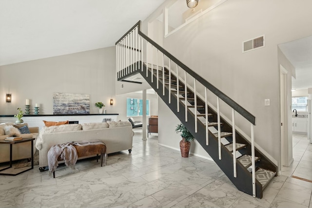 staircase featuring sink, plenty of natural light, and a high ceiling