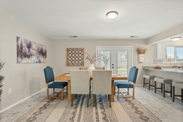 dining space featuring a textured ceiling and french doors