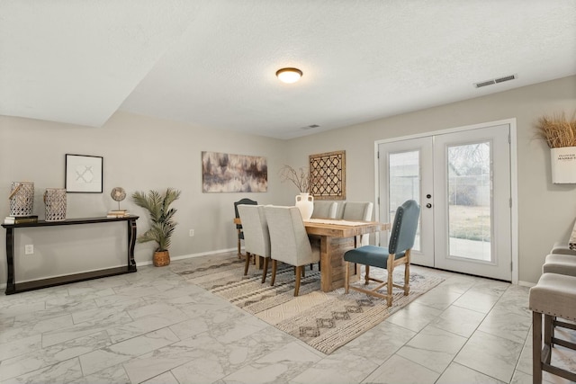 dining area featuring french doors and a textured ceiling