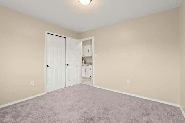 unfurnished bedroom featuring light colored carpet and a closet