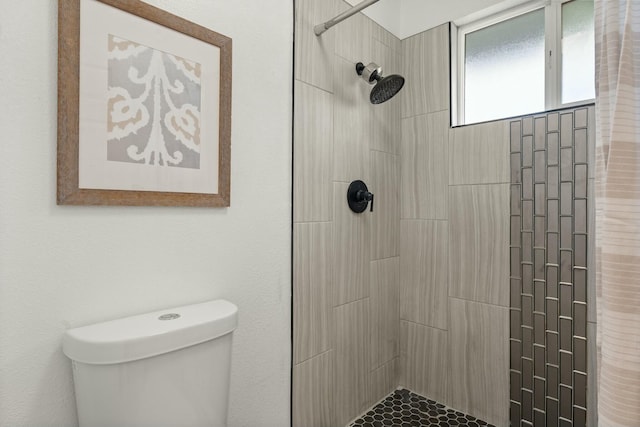 bathroom featuring toilet and a tile shower