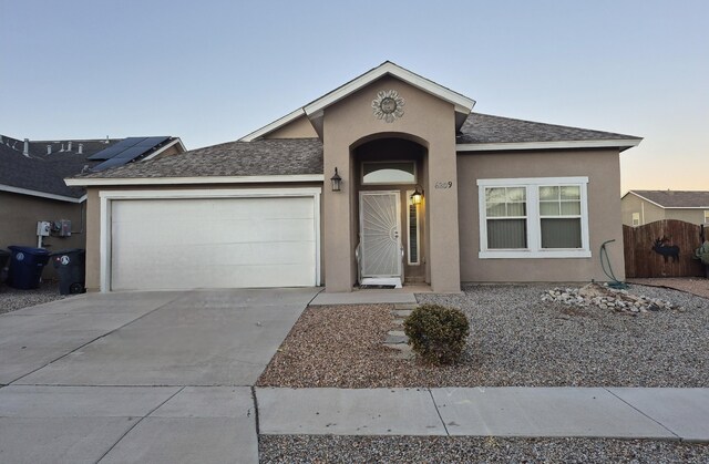 ranch-style home featuring solar panels and a garage