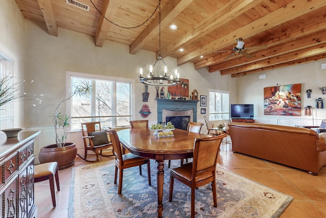 tiled dining space featuring beam ceiling, wooden ceiling, and ceiling fan with notable chandelier