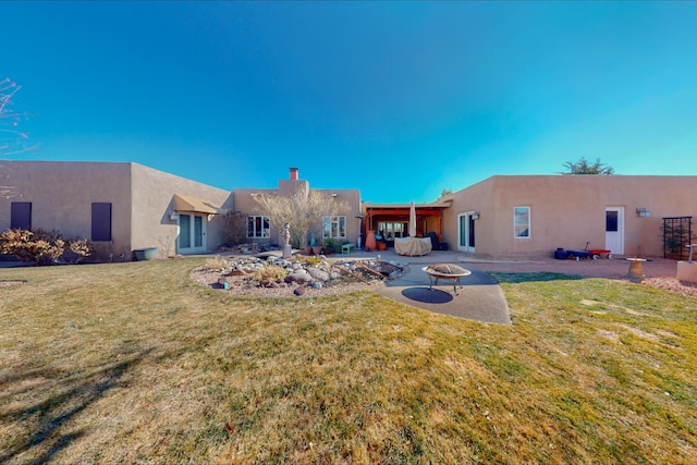 rear view of house with an outdoor fire pit, a patio, and a yard