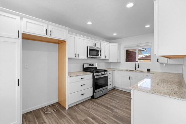 kitchen with light stone counters, stainless steel appliances, and white cabinetry