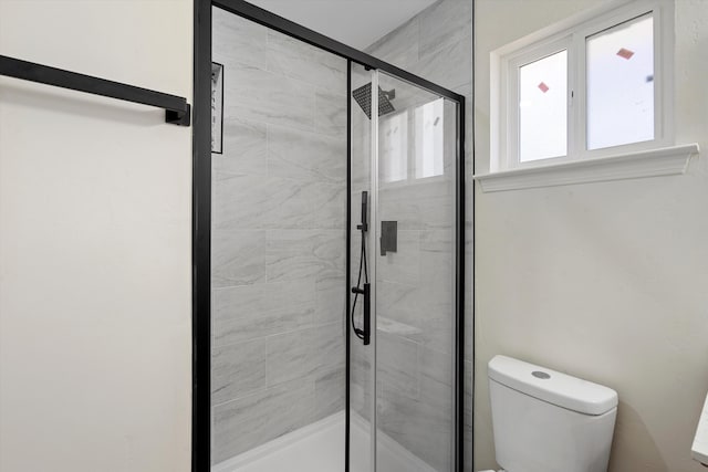 bathroom featuring a shower with shower door and toilet