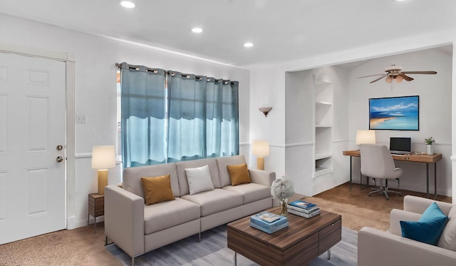 living room featuring built in features, ceiling fan, and carpet