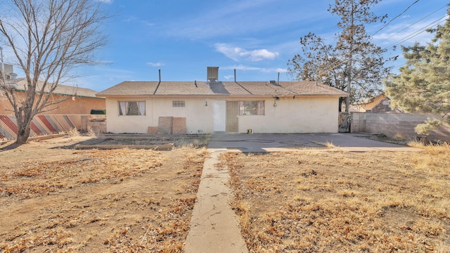 rear view of house featuring a patio area, fence, and stucco siding