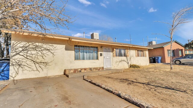 ranch-style house featuring cooling unit and stucco siding