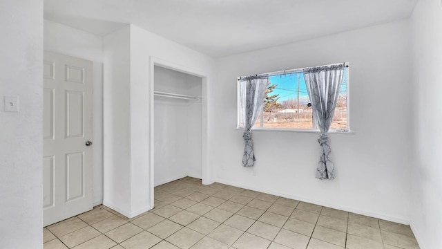 unfurnished bedroom with light tile patterned floors, baseboards, and a closet