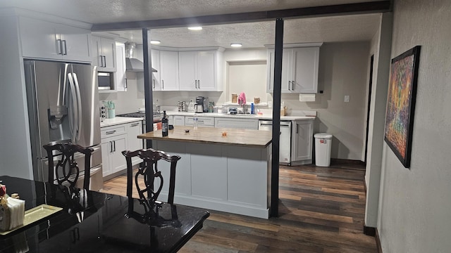 kitchen featuring a textured ceiling, appliances with stainless steel finishes, a kitchen island, dark hardwood / wood-style flooring, and beamed ceiling