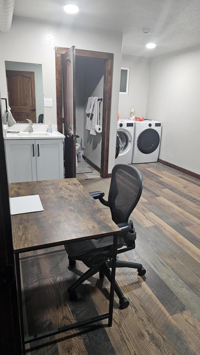 home office with light wood-type flooring, washer and clothes dryer, and sink