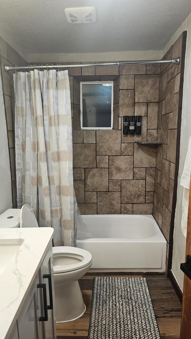 full bathroom with toilet, hardwood / wood-style floors, shower / tub combo, a textured ceiling, and vanity