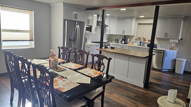 dining space with dark wood-type flooring, plenty of natural light, and a textured ceiling