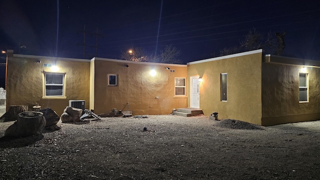 back house at night featuring central AC unit